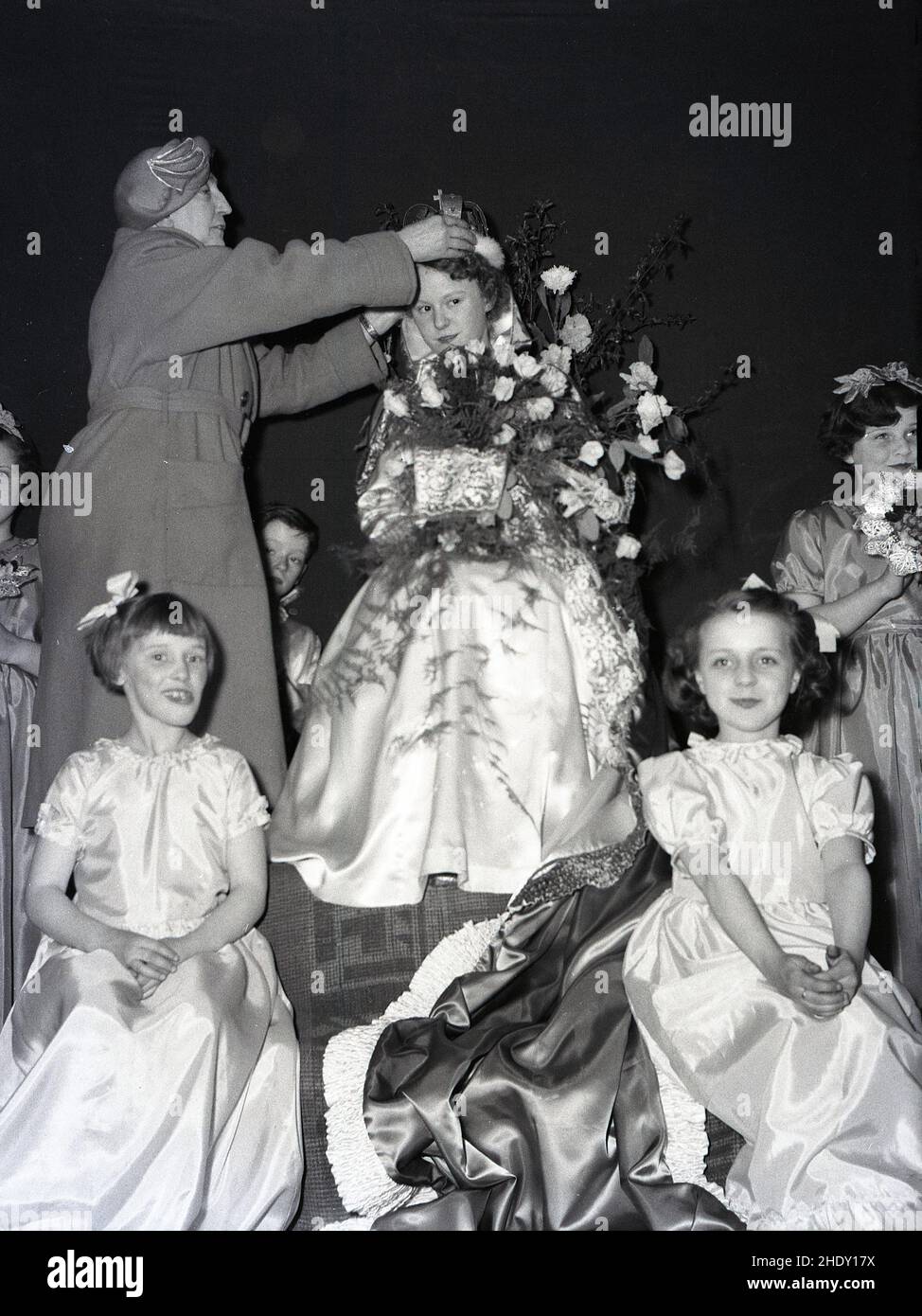1950s, historique, une dame ajustant la couronne sur la tête d'une jeune fille, la Reine de mai récemment couronnée, Angleterre, Royaume-Uni. Banque D'Images