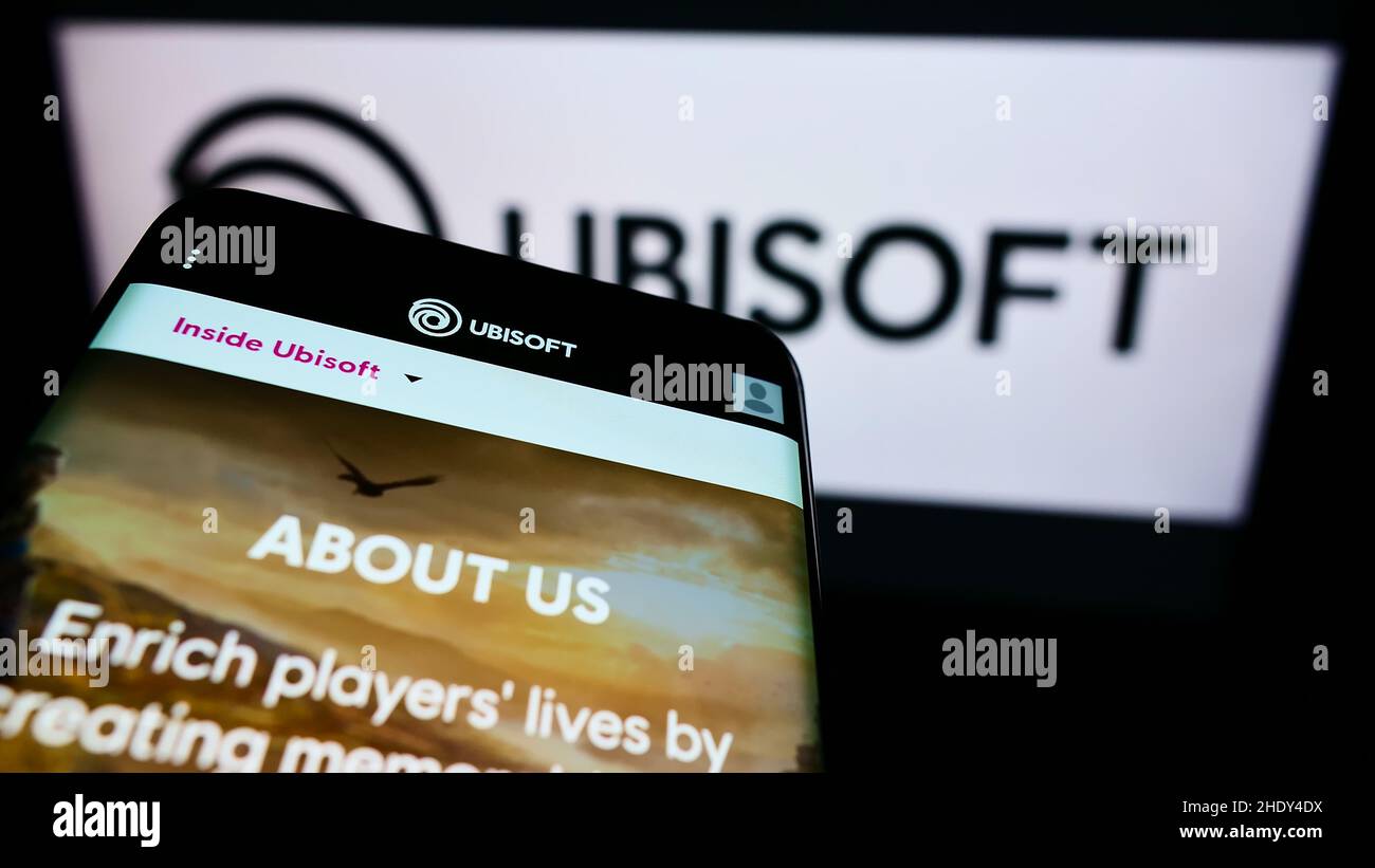 Téléphone mobile avec page web de la société française de jeux vidéo Ubisoft Entertainment sa à l'écran devant le logo.Faites la mise au point dans le coin supérieur gauche de l'écran du téléphone. Banque D'Images
