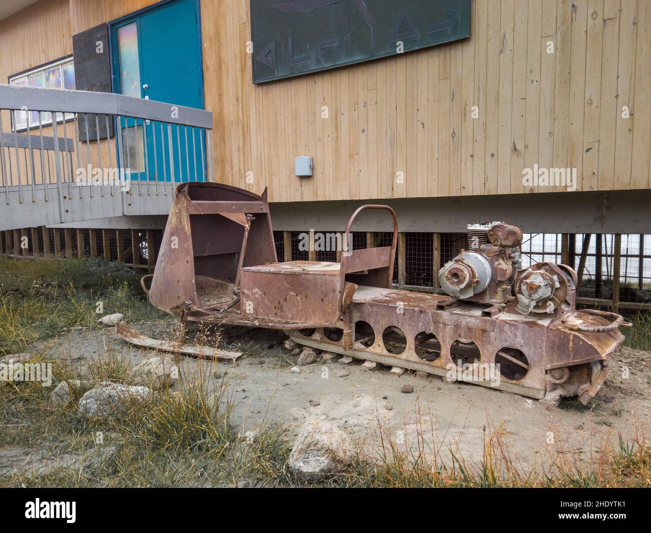 Pangnirtung, Canada - 09.03.2019 : ancienne épave rouillée de motoneige devant une maison en bois située sur le pergélisol dans la communauté inuite éloignée de Baffin Banque D'Images