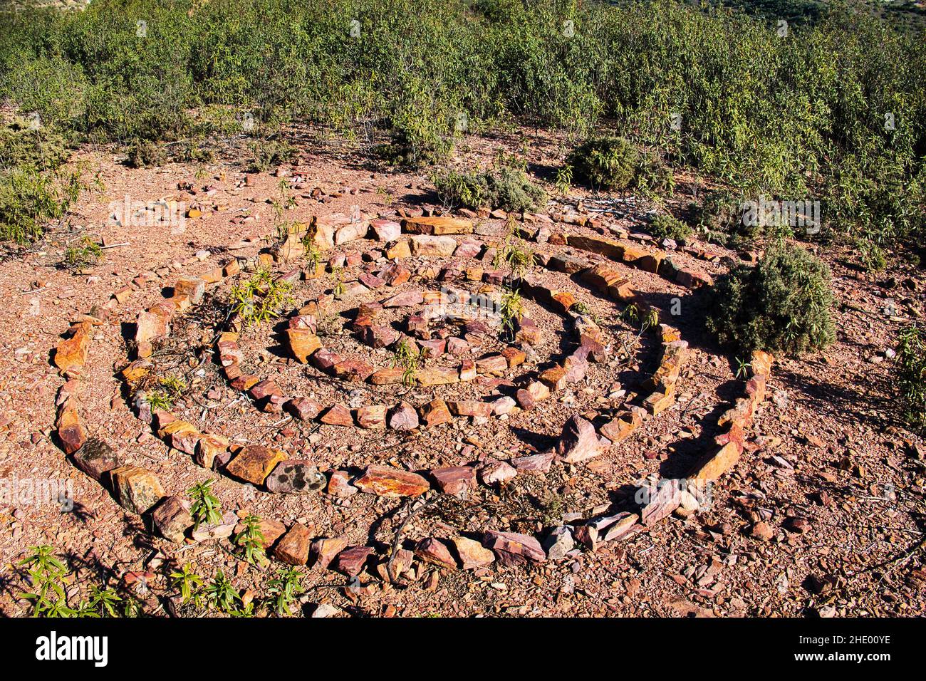 Pierres de différentes couleurs, disposées en spirale et en cercle, dans les collines couvertes de cistus près de Vale Fuzeiros, Algarve, Portugal Banque D'Images