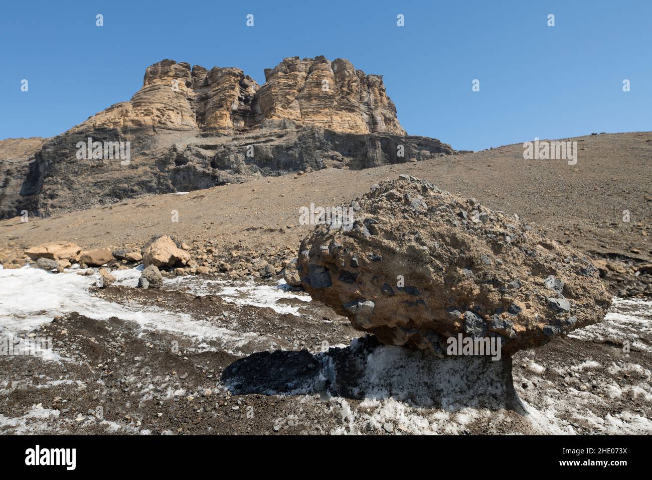 Un rocher est laissé sur un piédestal de glace alors que le glacier de Brown Bluff en Antarctique fond. Banque D'Images