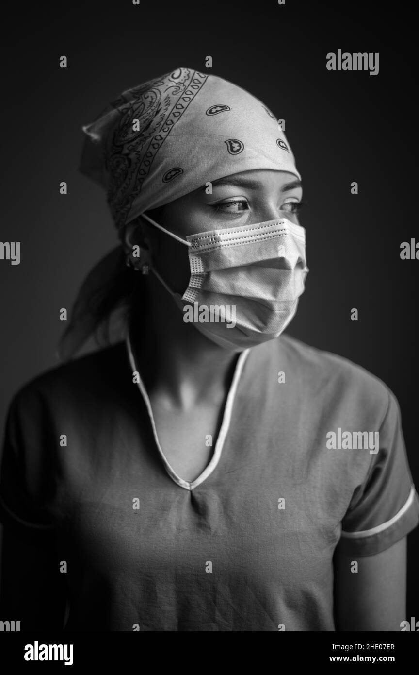 Portrait intime à l'intérieur de la travailleuse de santé latina portant un masque facial et une casquette d'infirmière pendant la pandémie Covid-19 Banque D'Images