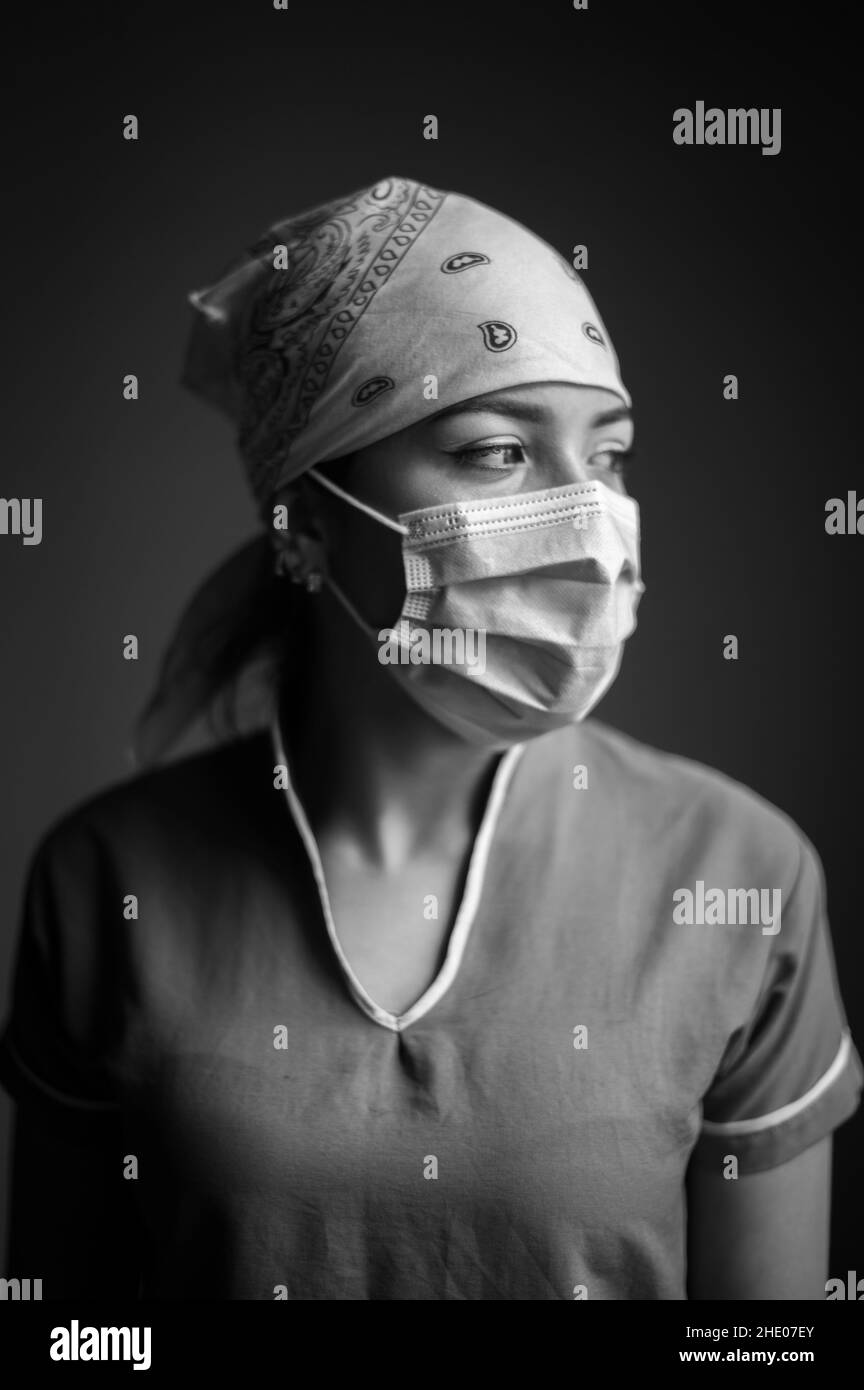 Portrait intime à l'intérieur de la travailleuse de santé latina portant un masque facial et une casquette d'infirmière pendant la pandémie Covid-19 Banque D'Images