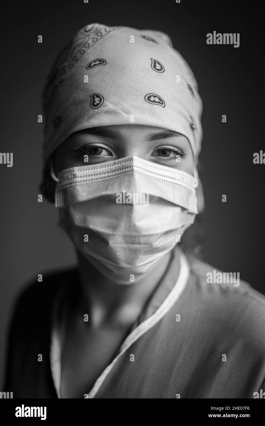 Portrait intime à l'intérieur de la travailleuse de santé latina portant un masque facial et une casquette d'infirmière pendant la pandémie Covid-19 Banque D'Images