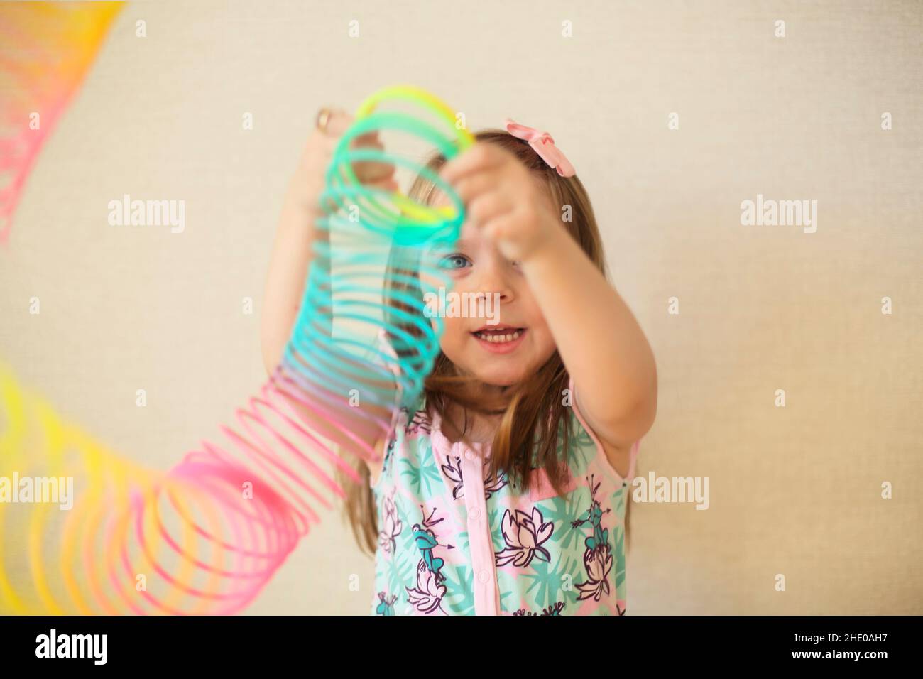 Adorable adorable petite fille jouant avec un ressort magique en plastique  arc-en-ciel, tenant un jouet élastique et souriant à l'appareil  photo.Joyeux enfant isolé sur la ba beige Photo Stock - Alamy