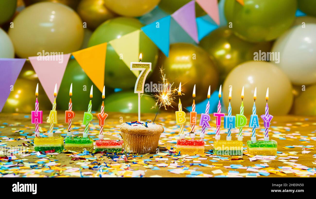 Carte de vœux pour un enfant de 7 ans, gâteau d'anniversaire avec bougies et décorations d'anniversaire sur fond Banque D'Images