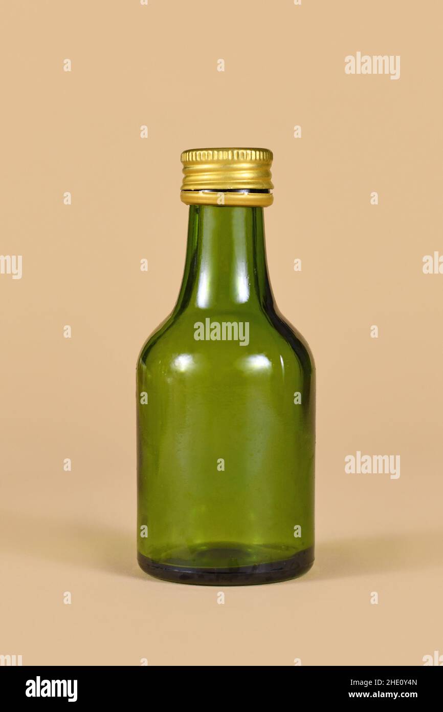 Une bouteille vide en verre vert sur fond beige Banque D'Images