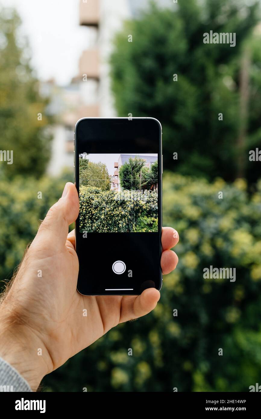 Paris, France - 2 octobre 2018 : main masculine tenant de nouveaux ordinateurs Apple iPhone se smartphone prenant une photo de jardin vert - image carrée Banque D'Images