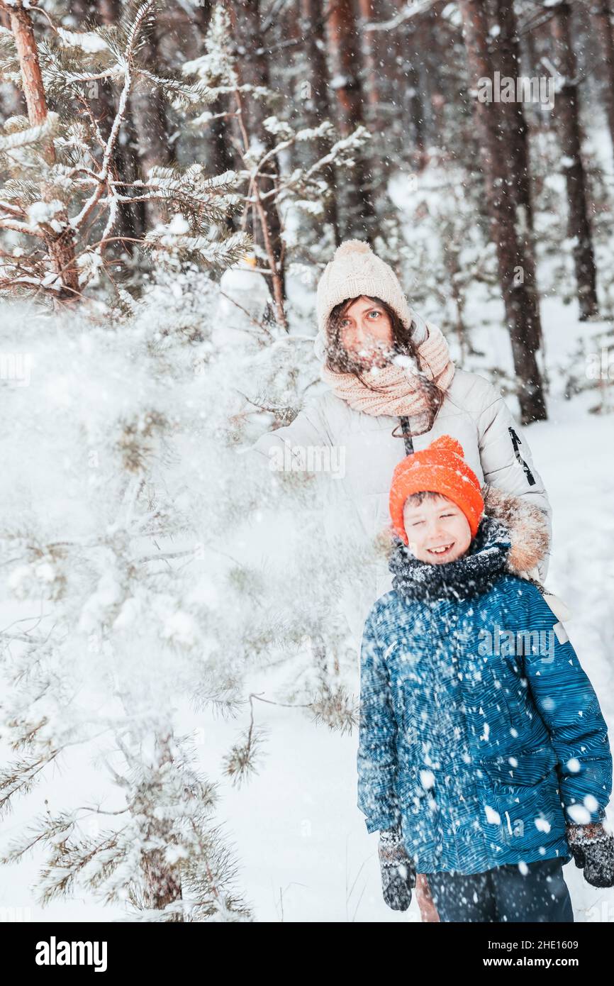 maman et fils jouent des boules de neige dans la forêt d'hiver.Maman marche avec son fils dans une chute de neige dans la forêt.Joyeuses vacances d'hiver avec la neige.Promenades en hiver Banque D'Images