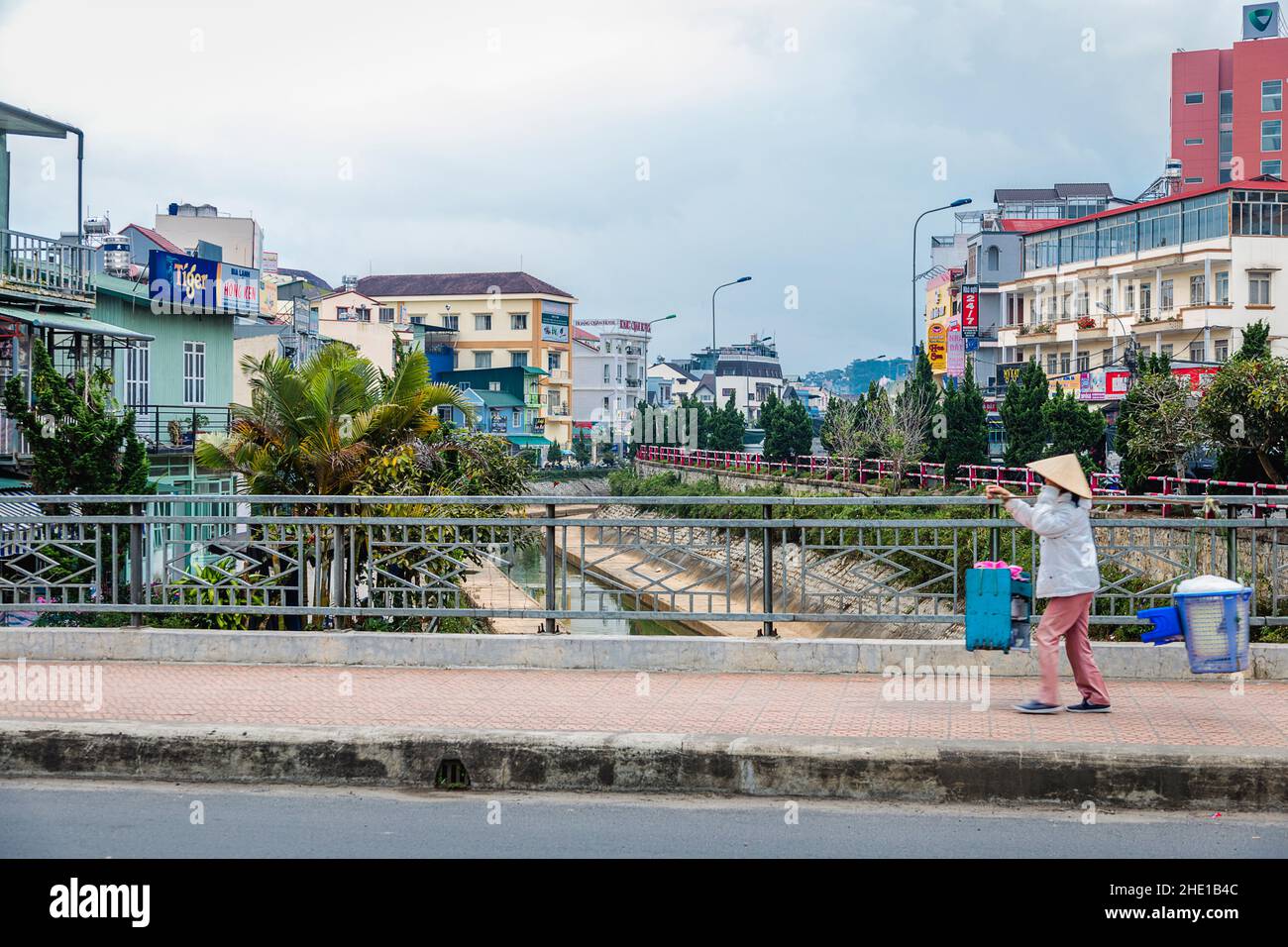 Une dame vietnamienne utilise un poteau pour transporter ses produits en vente sur le canal de drainage. Banque D'Images