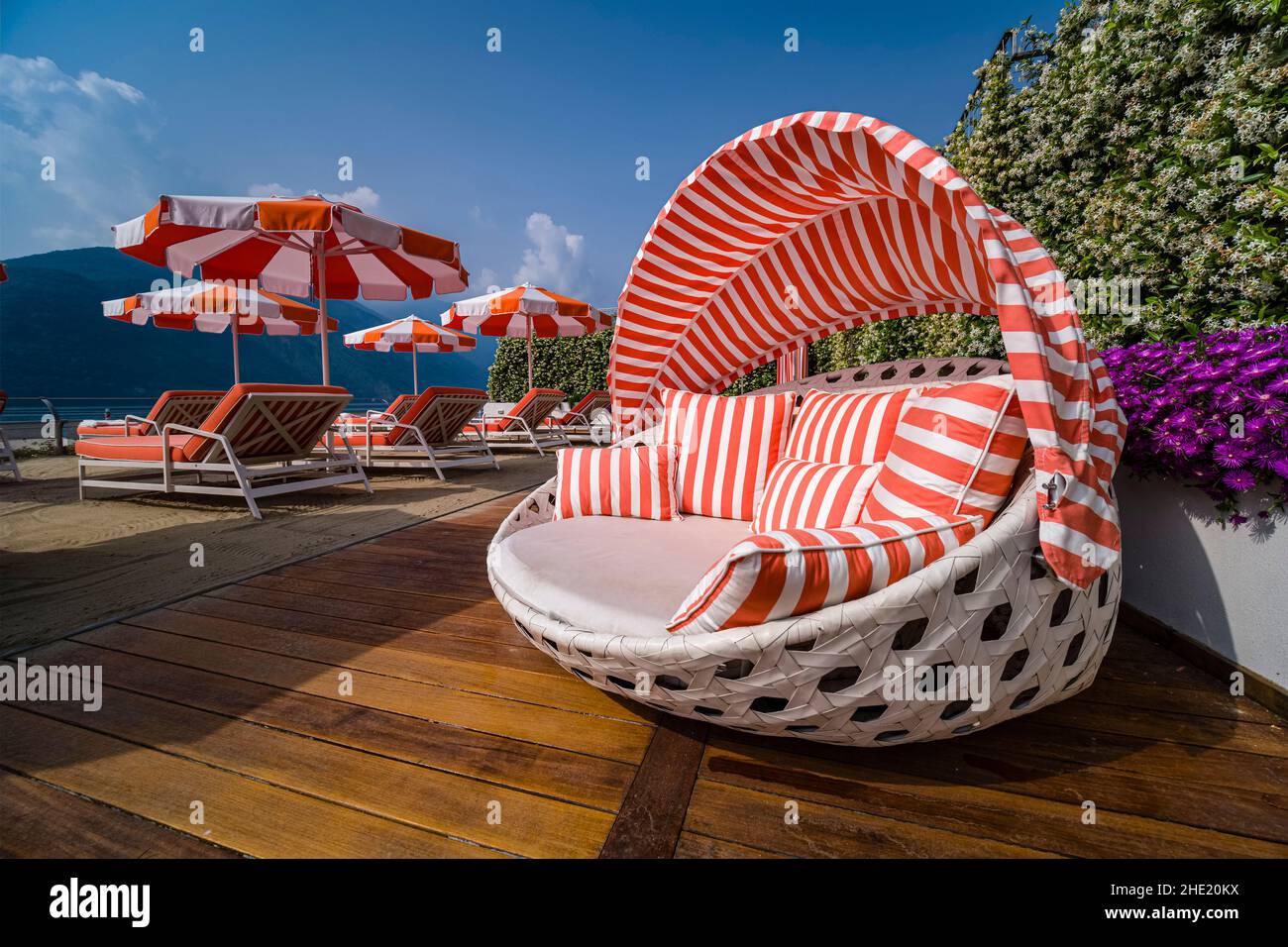 Des chaises longues orange et blanches et des parasols sont installés au bord du lac du Grand Hotel Tremezzo. Banque D'Images