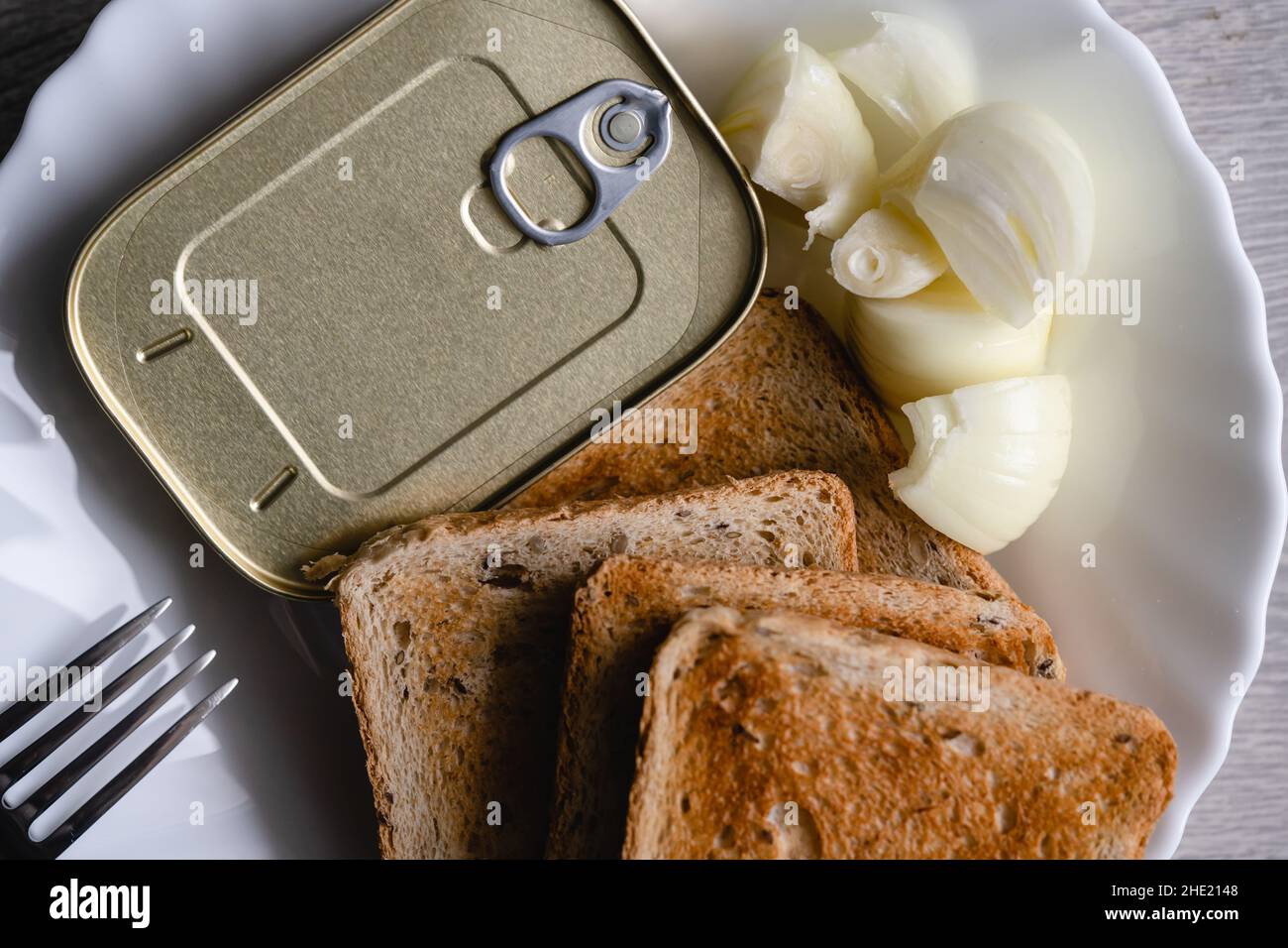 Gros plan sur l'assiette avec pain grillé oignon haché et boîte avec sardines en conserve nourriture de poisson jeûne concept Banque D'Images