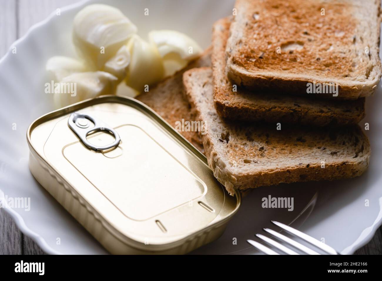 Gros plan sur l'assiette avec pain grillé oignon haché et boîte avec sardines en conserve nourriture de poisson jeûne concept Banque D'Images