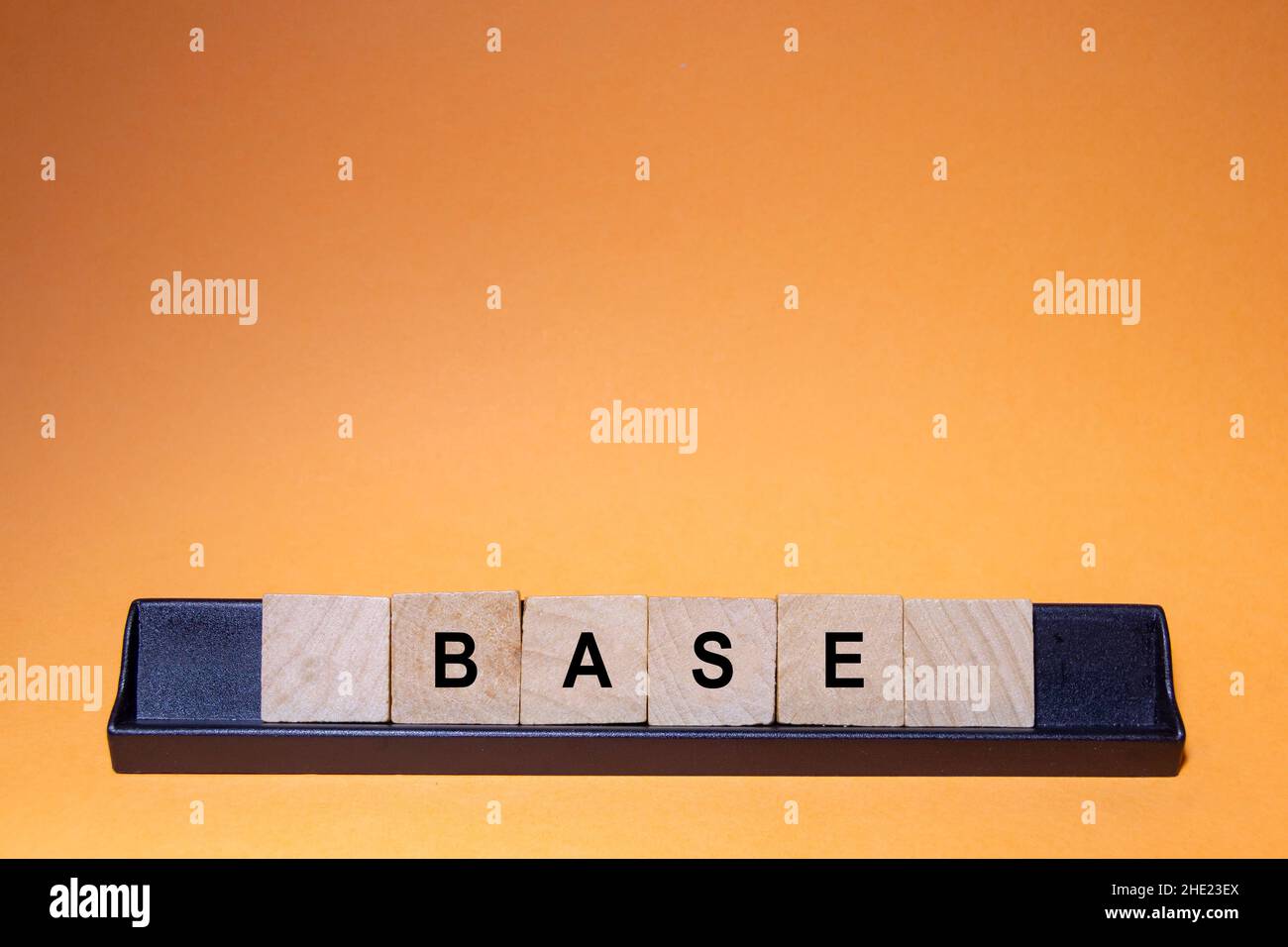 BASE.Mot écrit sur des carreaux carrés en bois avec un fond orange.Photographie horizontale. Banque D'Images