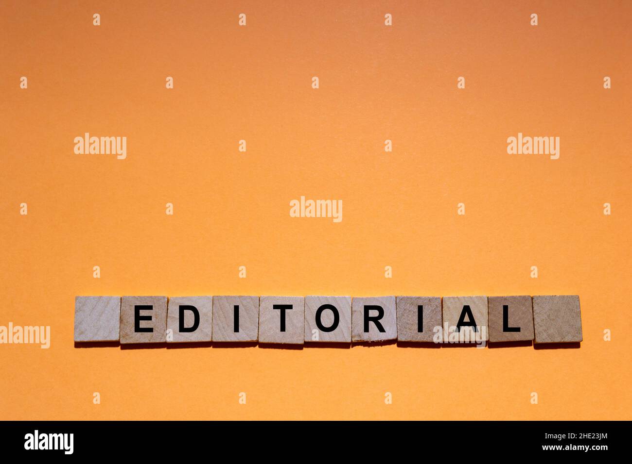 ÉDITORIAL.Mot écrit sur des carreaux carrés en bois avec un fond orange.Photographie horizontale. Banque D'Images