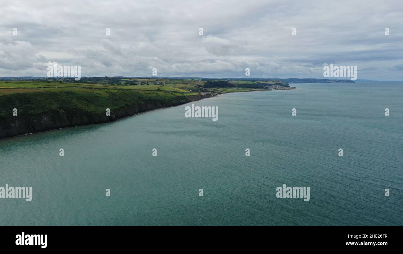 Image aérienne de la côte galloise et de la falaise à Llannon, Ceredigion.Ciel bleu et mer, plage de galets, sentier côtier. Banque D'Images