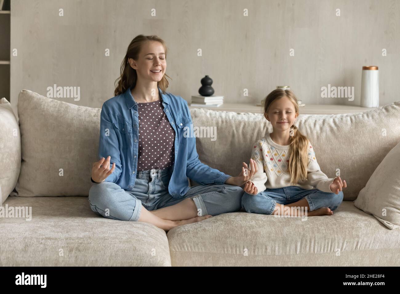 Décontracté et paisible jeune mère et petite fille faisant des exercices de yoga. Banque D'Images