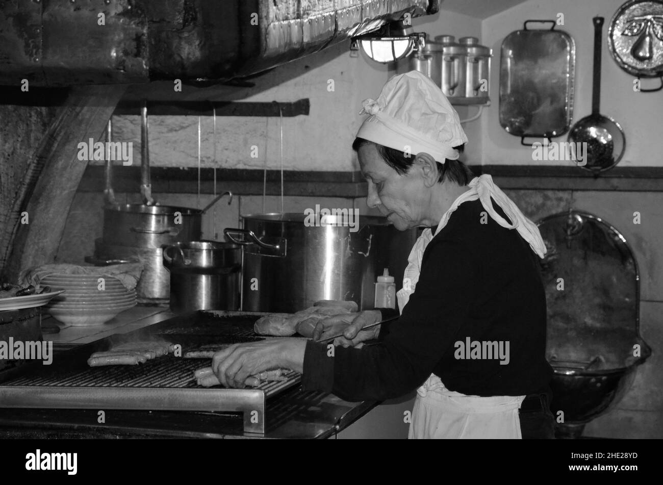 Ratisbonne, Bavière, Allemagne - 11.11.2014: Une femme prépare des saucisses traditionnelles allemandes grillées.Gashtet dans la vieille ville. Banque D'Images