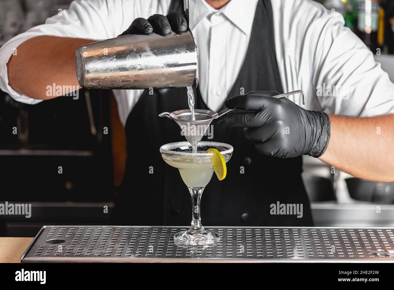 Barman professionnel avec un shaker dans ses mains faisant un cocktail alcoolique Margarita. Banque D'Images