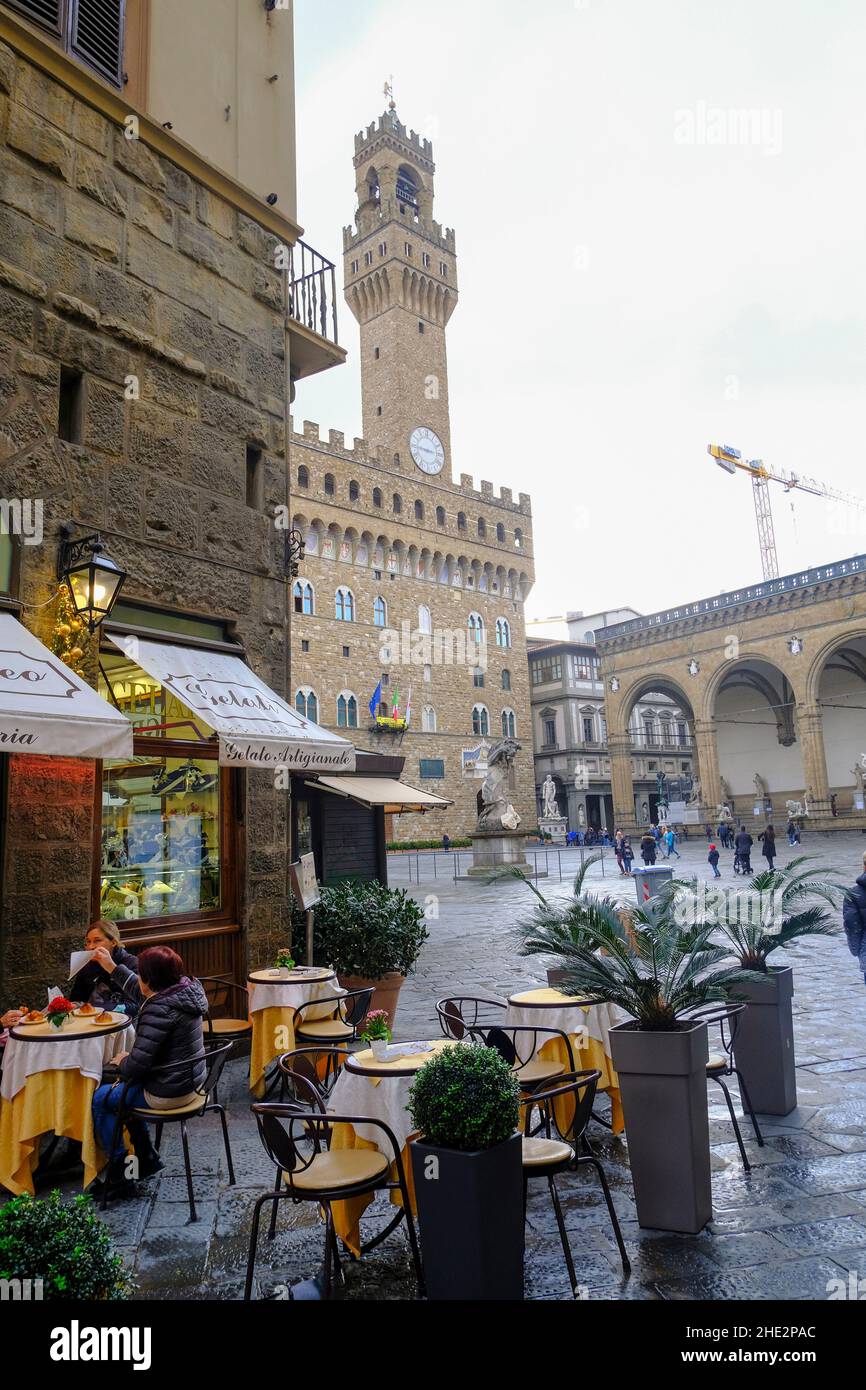2021 décembre Florence, Italie: Café avec les gens sur la place. piazza della Signoria de l'autre côté de la tour du Palazzo Vecchio Banque D'Images