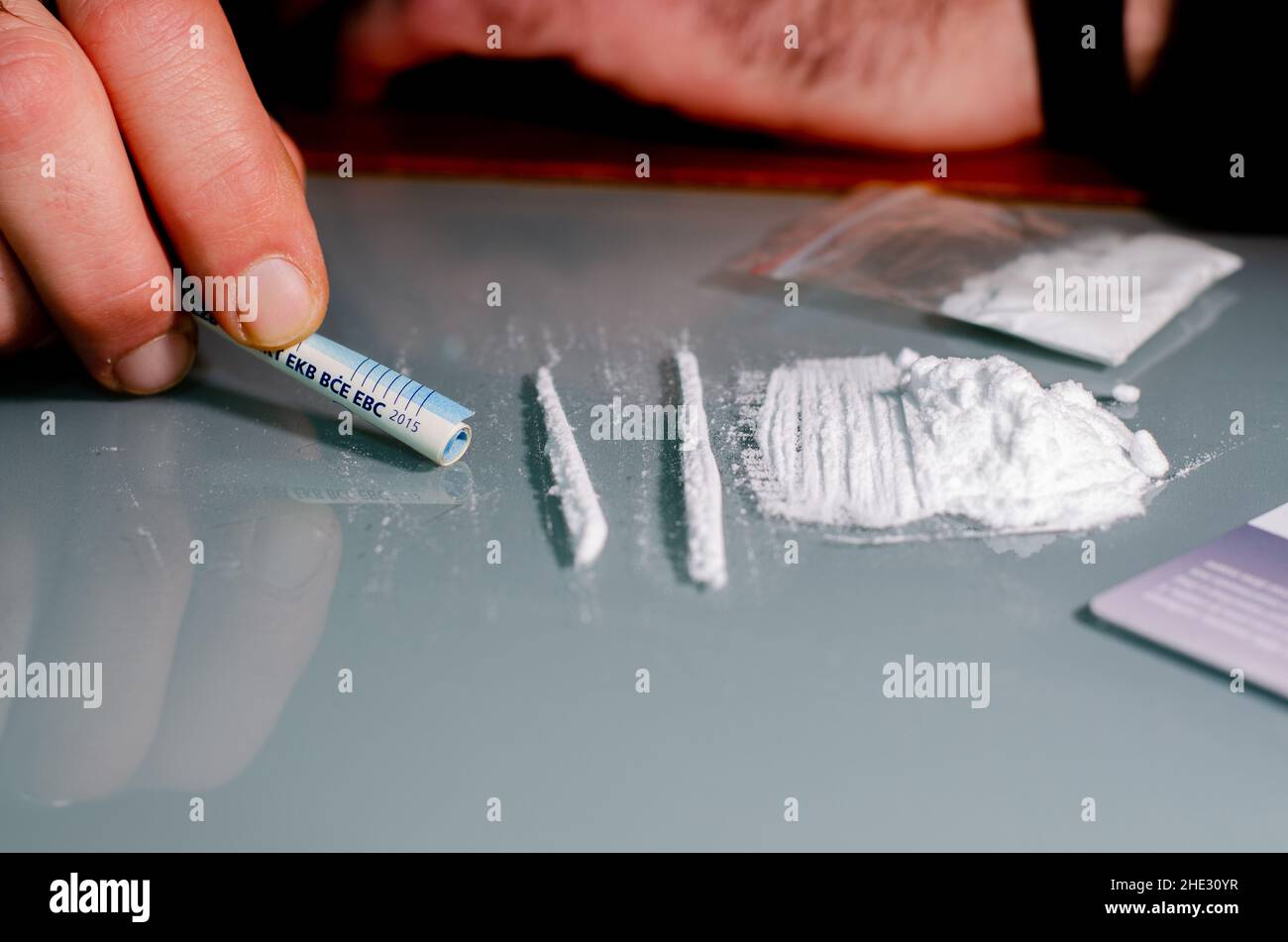 L'homme est sur le point d'arrater de la cocaïne avec des billets de banque roulés.Concept de narcotiques. Banque D'Images