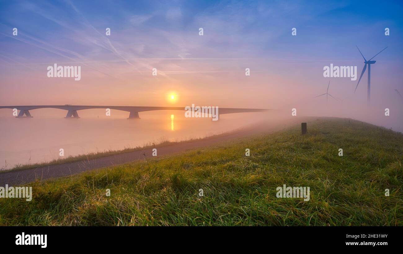 Long pont sur l'eau douce et vivivivivivivivile allant à l'infini au-dessus de l'océan magnifique sous le magnifique ciel coloré de Zeeland, aux pays-Bas Banque D'Images