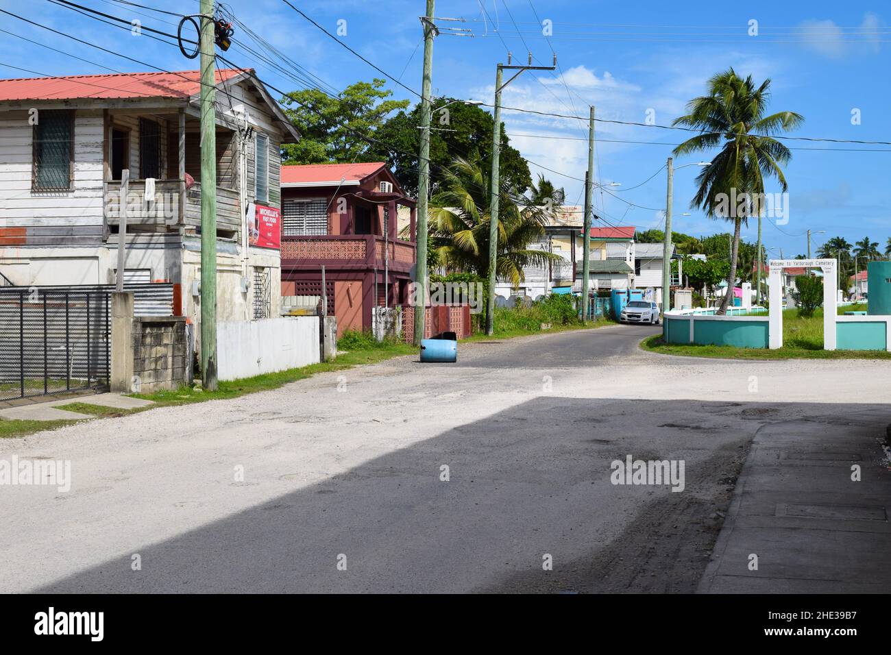 Une rue de Belize City Belize avec des maisons et un cimetière. Banque D'Images