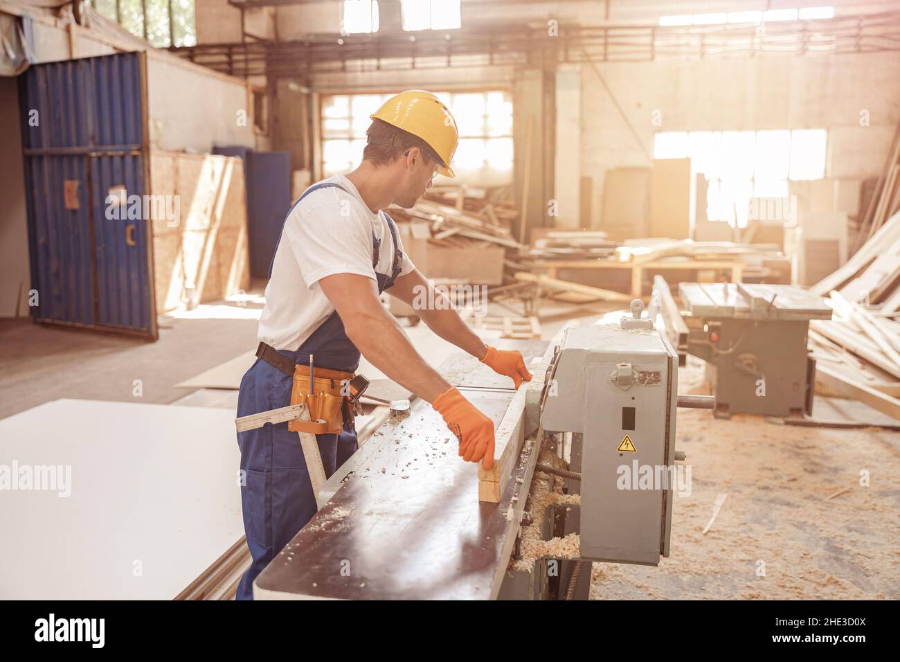 Travailleur masculin utilisant une machine à bois dans un atelier de menuiserie Banque D'Images