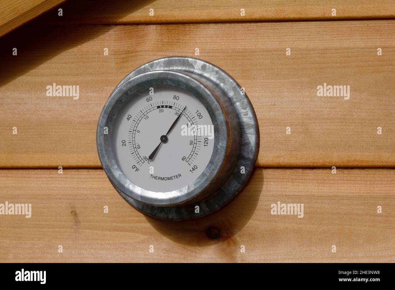 Un thermomètre de jardin au soleil direct montrant 86 Fahrenheit le jour d'été de juin. Banque D'Images