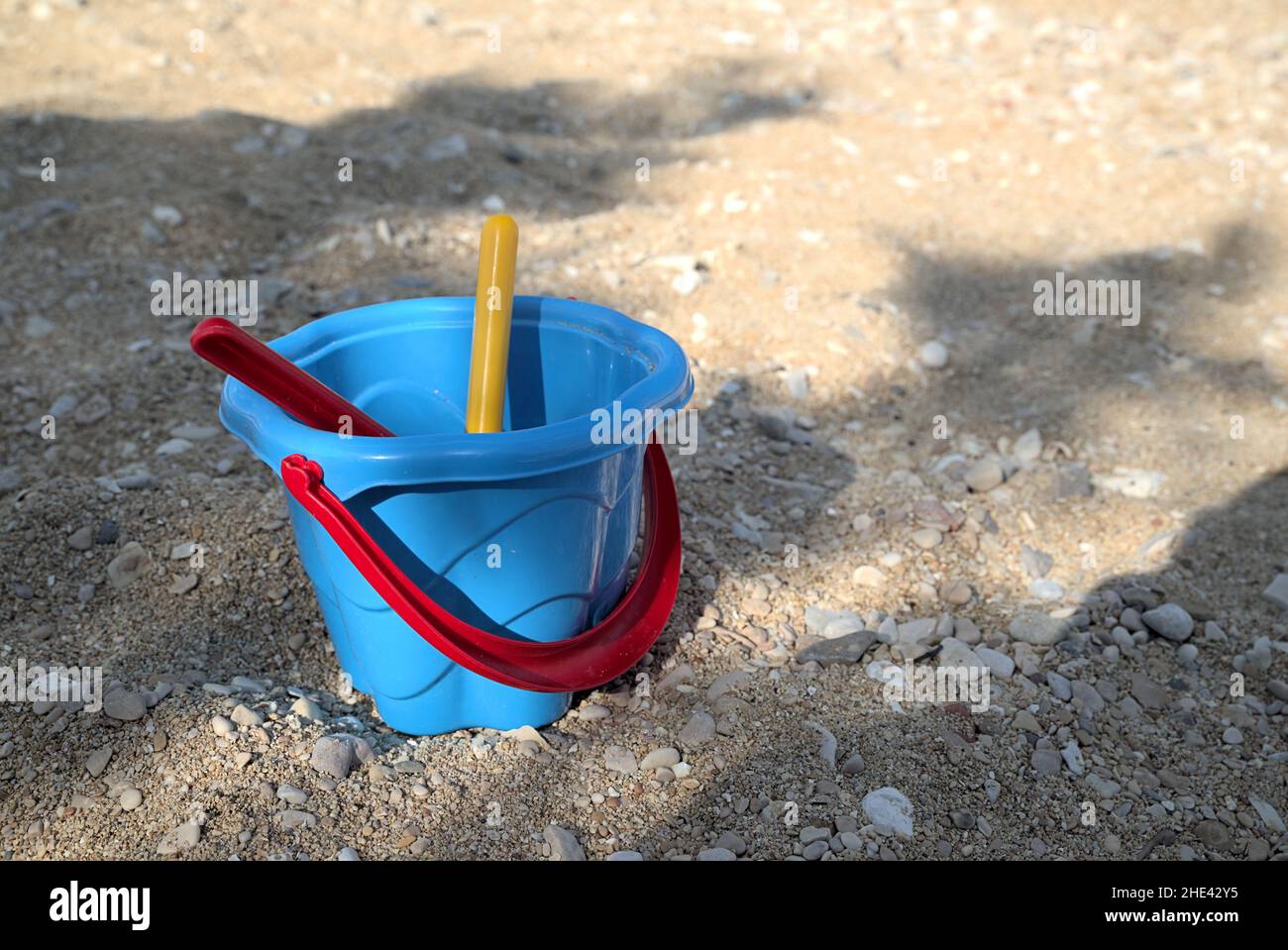 Seau bleu avec la hile rouge sur la plage Banque D'Images