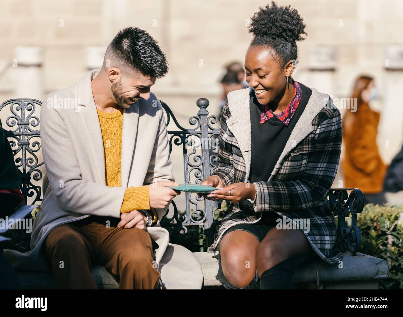Homme et femme échangeant des cadeaux tout en étant assis sur un banc à l'extérieur Banque D'Images
