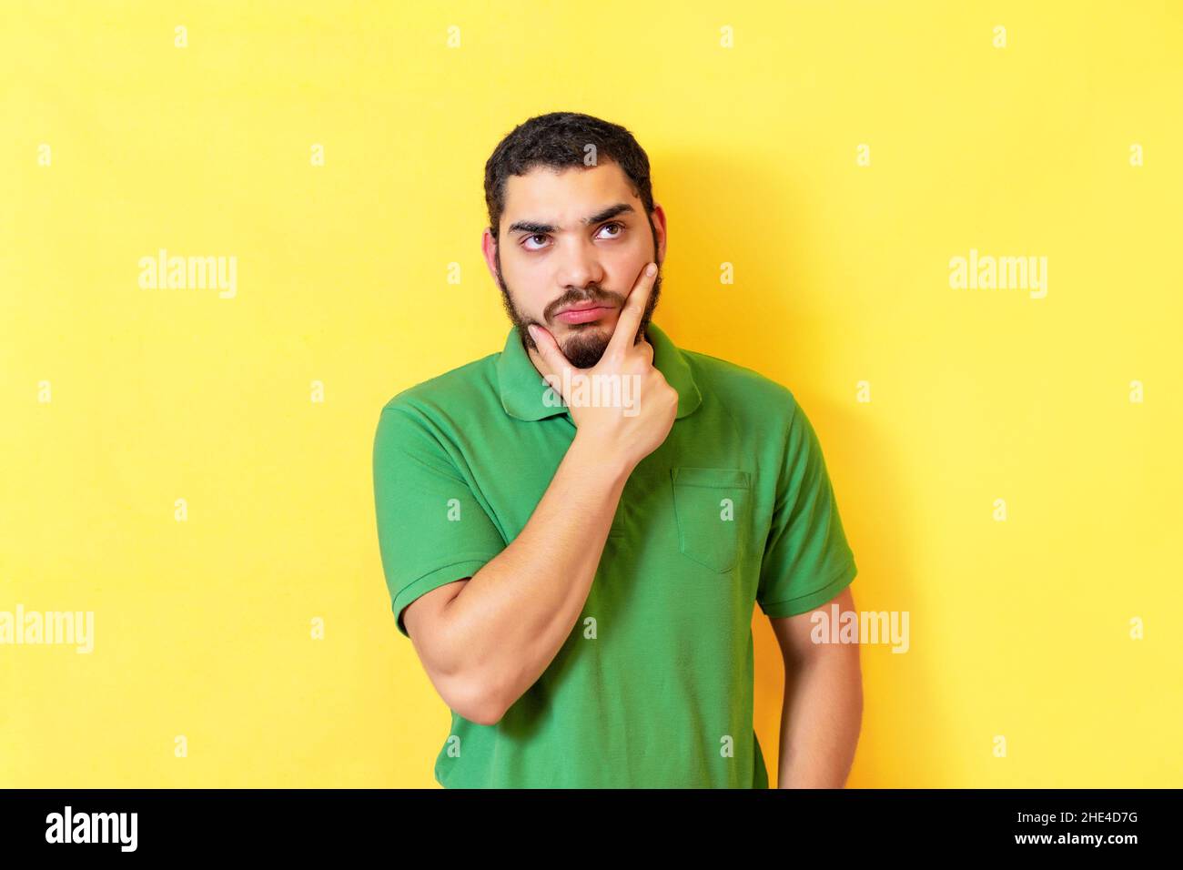 Jeune homme sérieux et pensif, isolé sur un mur jaune. Banque D'Images