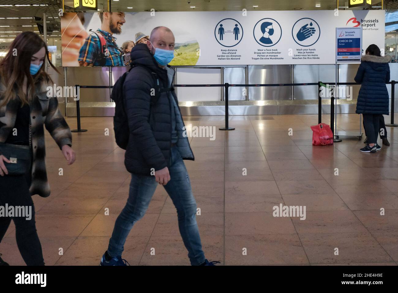 Zaventem, Belgique.8th janvier 2022.Les gens marchent devant un panneau rappelant aux gens les mesures contre le COVID-19 à l'aéroport de Bruxelles à Zaventem, en Belgique, le 8 janvier 2022.Selon l'institut de santé belge Sciensano, la Belgique a récemment enregistré une augmentation du nombre de cas de COVID-19, avec une moyenne quotidienne de 15 996 au cours de la période allant du 29 décembre 2021 au 4 janvier 2022.Credit: Zhang Cheng/Xinhua/Alay Live News Banque D'Images