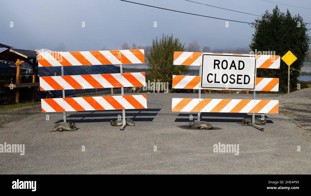 Carnation, WA, États-Unis - 31 octobre 2021; Un panneau de signalisation fermé et une paire de barrières rayées bloquent une route rurale Banque D'Images
