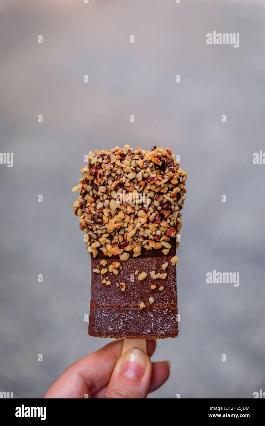 Femme tenant une barre de glace au chocolat avec noisette d'une petite boutique artisanale du pays Basque, Donostia ou San Sebastian, Espagne Banque D'Images