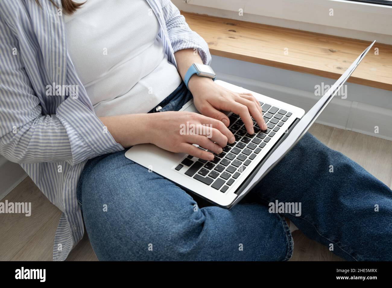 Femme d'âge moyen travaillant à domicile.Fille utilisant un ordinateur portable à la maison, assis près d'une grande fenêtre.Concept de travail à distance Banque D'Images