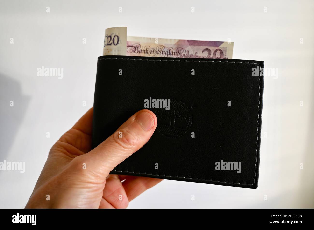 Gros plan d'un homme tenant un portefeuille contenant un billet de vingt livres. Banque D'Images