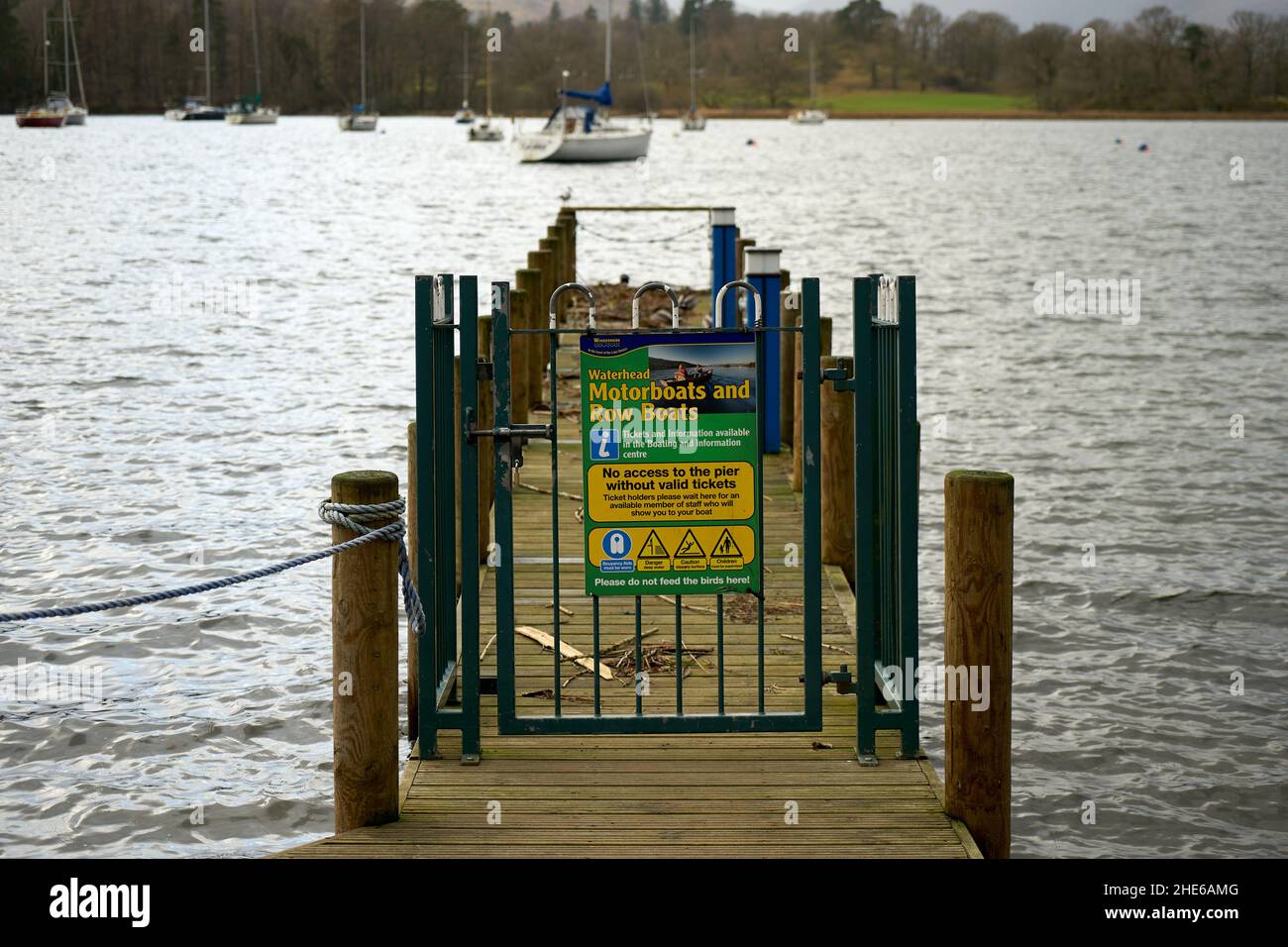 Une porte en métal au bout d'une jetée avec un panneau informant de la location d'un bateau à moteur et d'un bateau à ramer sur le lac Windermere, Cumbria, Royaume-Uni Banque D'Images