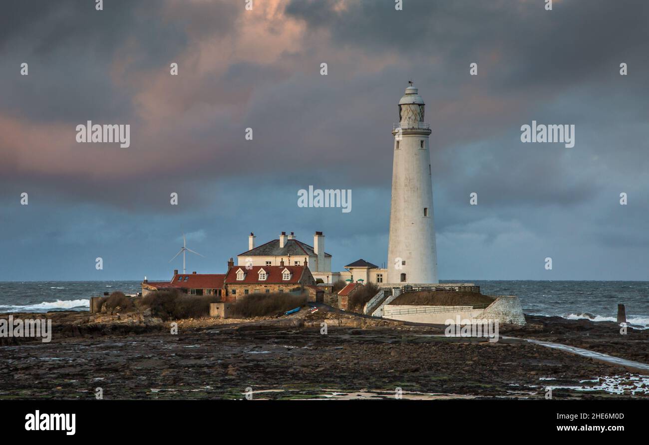 Big Clouds survolent le phare de St. Mary's dans la baie Whitley à marée basse, avec la chaussée de marée en vue Banque D'Images
