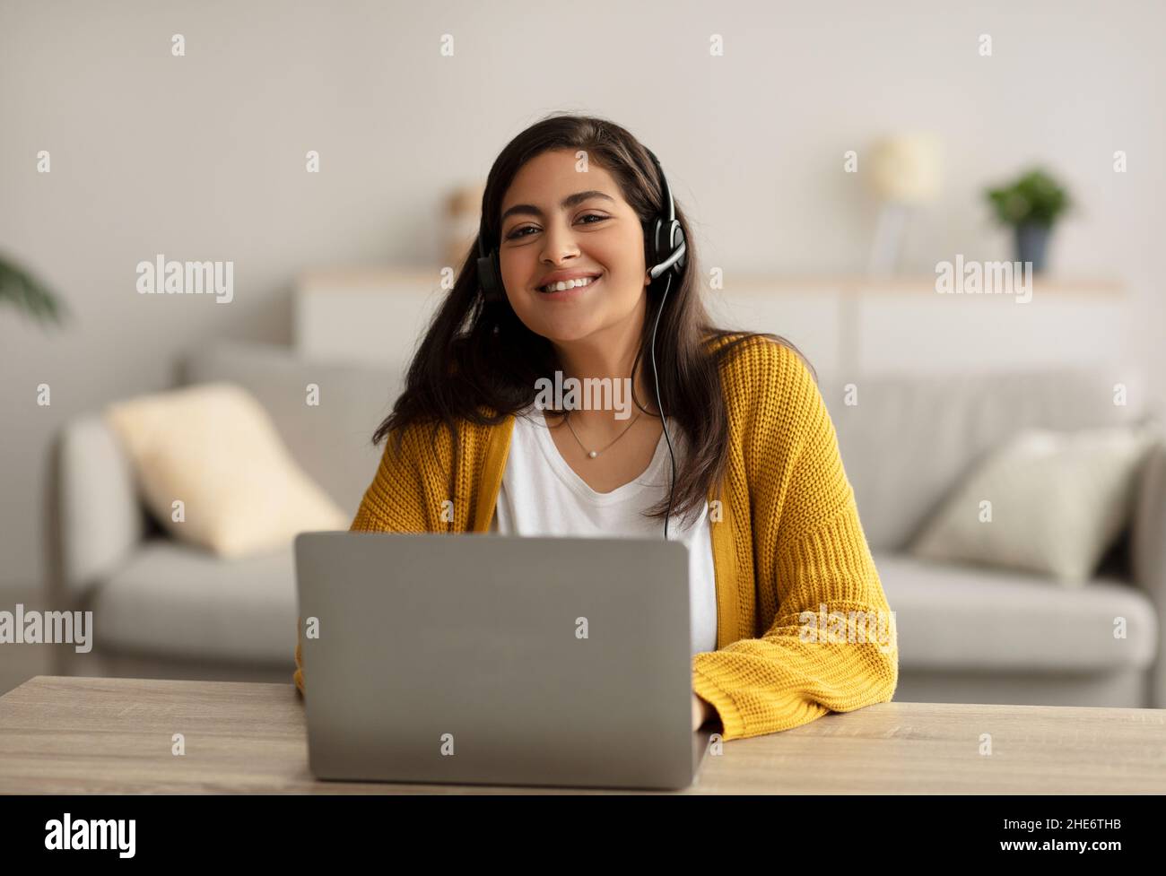 Concept d'apprentissage en ligne.Bonne femme arabe portant un casque et étudiant en ligne avec un ordinateur portable à la maison, assis au bureau Banque D'Images