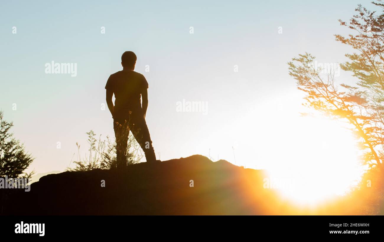 Silhouette d'un homme debout sur un rocher et un lever de soleil - le concept d'un nouveau commencement Banque D'Images