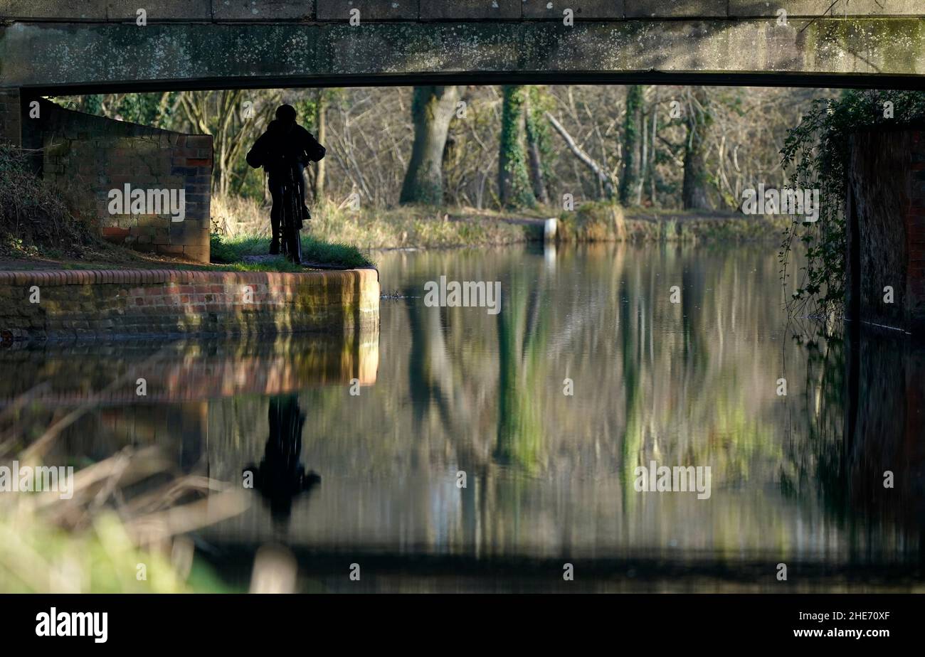 Un cycliste suit un chemin de remorquage près du canal de Basingstoke, près de Church Crookham, dans le Hampshire.Date de la photo: Dimanche 9 janvier 2022. Banque D'Images