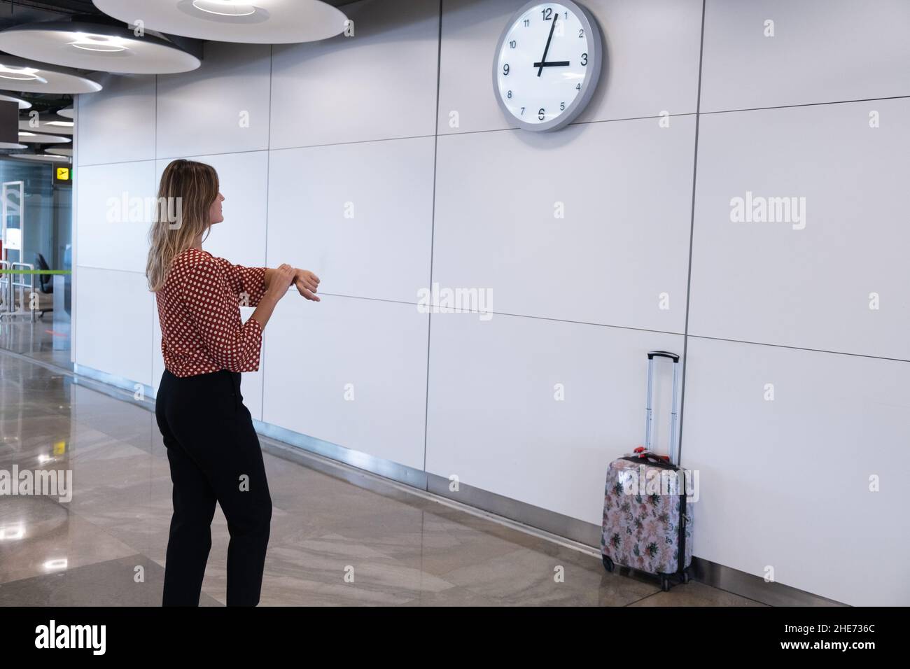 une jeune femme regarde l'heure à l'aéroport Banque D'Images