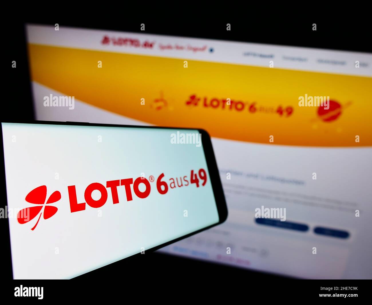 Smartphone avec logo de la loterie allemande Deutsche Lotto- und Totoblock à l'écran en face du site Web d'affaires.Mise au point à gauche de l'écran du téléphone. Banque D'Images