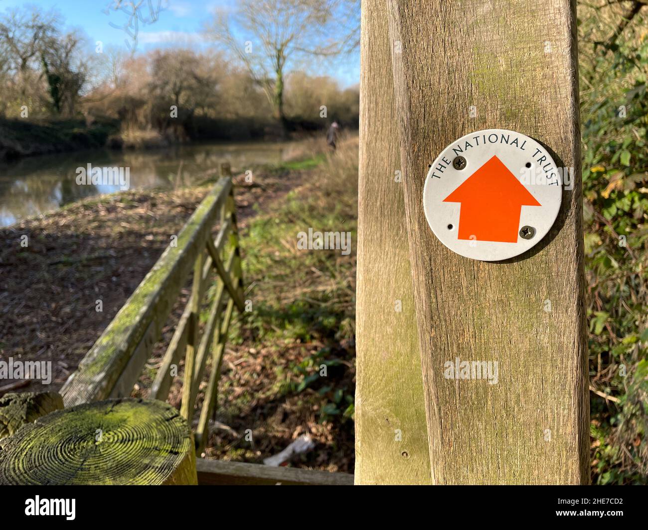 La signalisation sur un poteau de portail en bois a un panneau rond avec une flèche directionnelle orange et des mots The National Trust.Stour Valley Way Banque D'Images