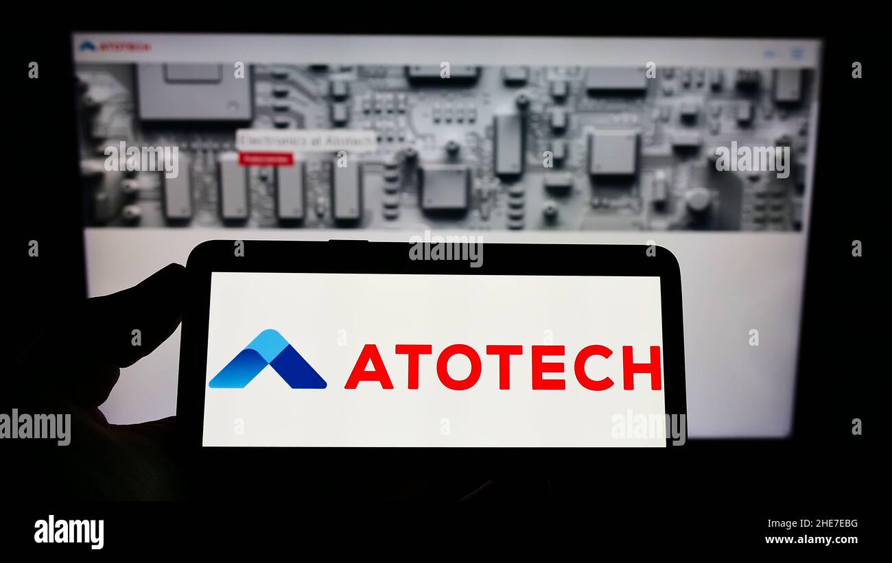 Personne tenant un smartphone avec le logo de la société chimique Atotech Deutschland GmbH à l'écran devant le site Web.Mise au point sur l'affichage du téléphone. Banque D'Images