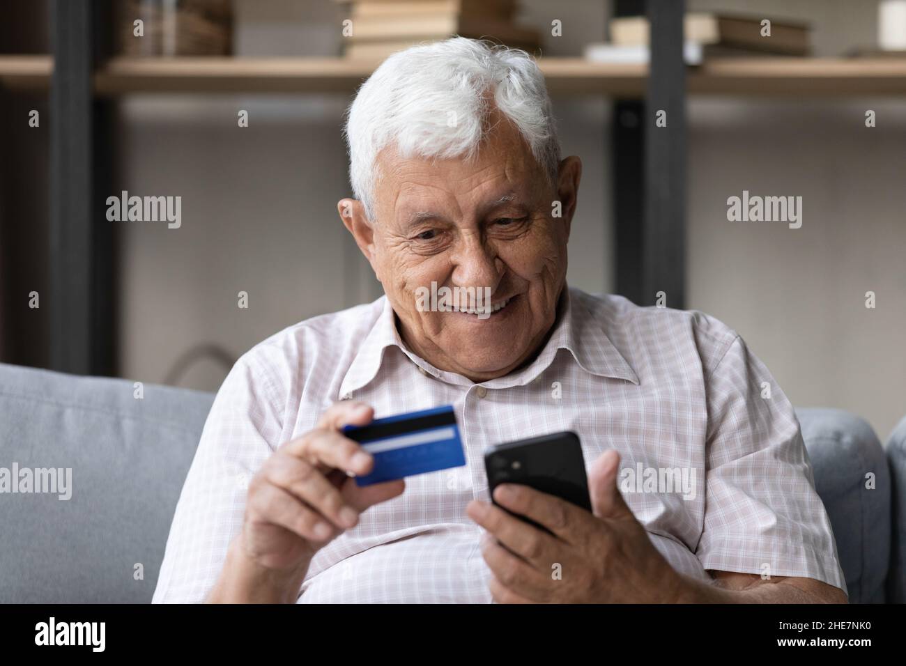Joyeux homme retraité qui fait ses achats dans une application mobile. Banque D'Images