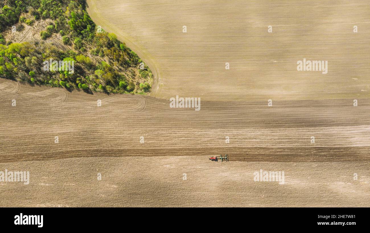 Le tracteur labourage le champ au printemps. Début de la saison agricole. Cultivateur tiré par UN tracteur en campagne rurale. Campagne Banque D'Images