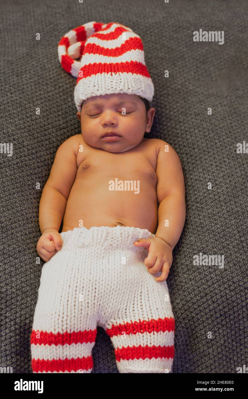 Le nouveau-né allongé dans un chapeau rayé est endormi avec ses mains clastées et ses jambes non cassées Banque D'Images