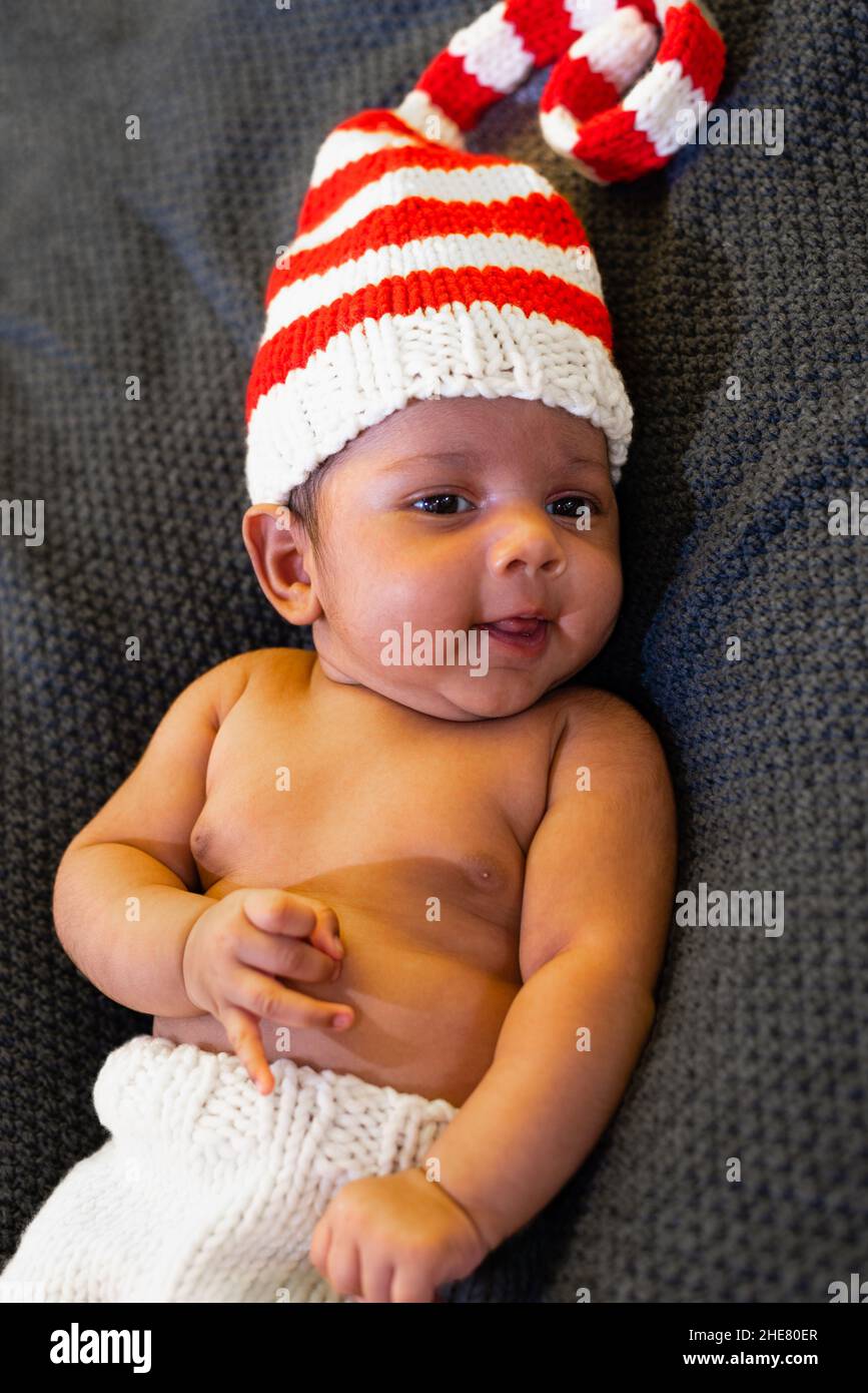 Le nouveau-né allongé dans un chapeau rayé regarde devant sa bouche est en souriant ouvertement Banque D'Images